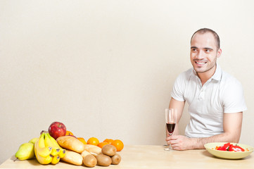 Portrait of a young man having a glass of wine while cooking. co