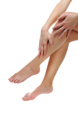 Close up of slender naked legs being massaged isolated on white