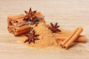 Cinnamon sticks, powder and anise on wooden table
