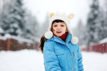 Cute toddler girl in snowsuit posing outdoors