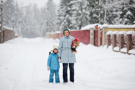 Young mother and her daughter in a snowfall