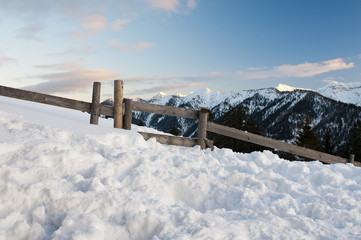 romantic tyrolean mountains at twilight, much snow, wooden fence