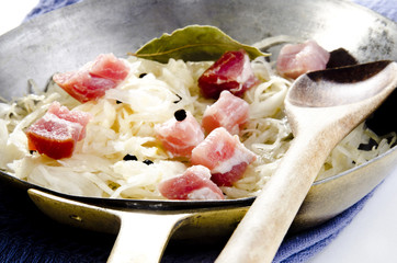 Sauerkraut with diced bacon and bay leaf in a pan