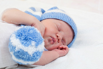 newborn baby  sleeps in a knitted striped hat