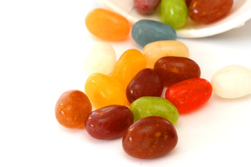 Colourful candies in a brown bowl on white background