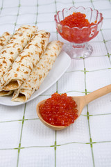 Pancakes with red caviar on a plate.