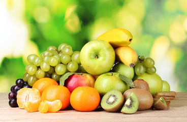 Ripe juicy fruits on wooden table on green background