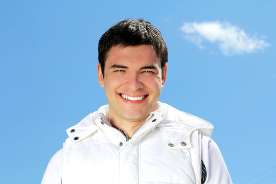 Portrait of attractive happy man on blue sky background outdoors