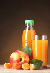 Nectarine and juice glass on wooden table on brown background