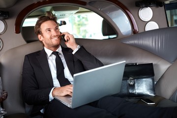 Smiling businessman in luxury car working
