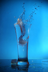 Water splash in glass on blue background