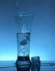 Water flows into the glass with ice