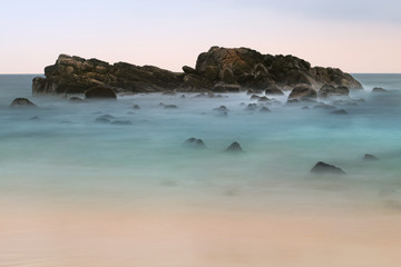 Rocks in the ocean on the horizon after sunset