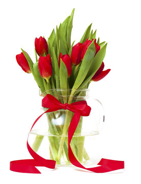 red tulips in a vase with a red ribbon
