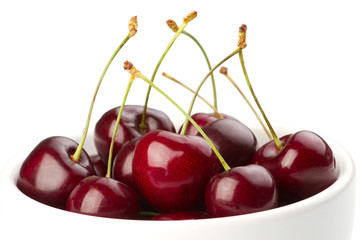 Red ripe cherries in a bowl on white background