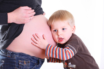 kleiner bruder horcht am babybauch der schwangeren mutter