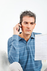 Mann mit Handy und Telefonrechnung