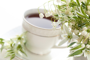 Fototapeta na wymiar tea in a cup of white flowers and lilies of the valley