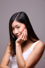 Fototapeta premium junge asiatin vor grauem hintergrund lächelt in die kamera