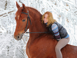 Girl horseback riding in the winter forest