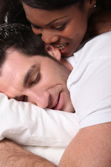 woman biting her husband's ear in bed