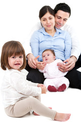 Unhappy jealous little girl with family