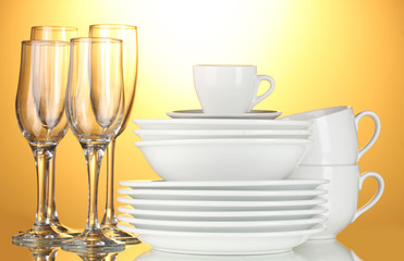 empty bowls, plates, cups and glasses on yellow background