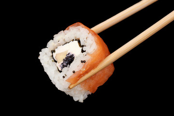 Holding roll with chopsticks isolated on black