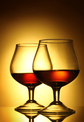 Two glasses of cognac on yellow background