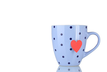Blue cup and tea bag with red heart-shaped label isolated