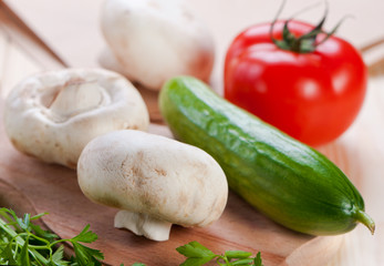 Mushrooms and vegetables on cutting board.