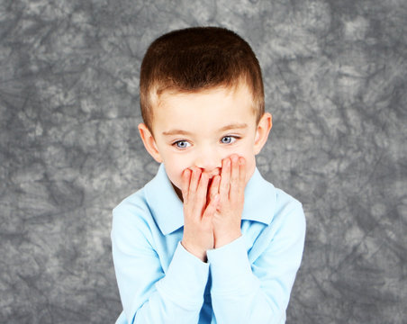 Young boy hiding face in hands