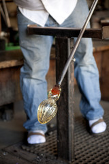 Glass blower shaping molten glass into a drinking goblet