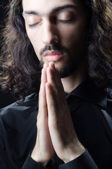 Young man praying in darkness