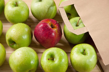 Red fresh apple lying on wooden boards among green ones