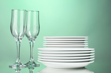 Clean plates and glasses on green background