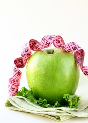 Diet concept Ripe green apple with measuring tape
