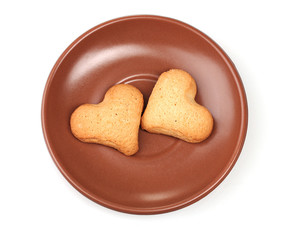 Two heart-shaped cookies on brown saucer isolated on white