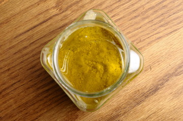 Vinaigrette sauce in glass jar on wooden table, top view