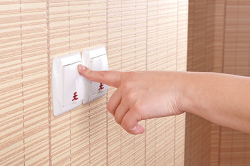 Hand pressed to switch on the wall
