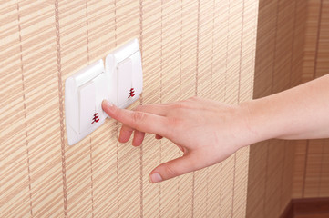 Hand pressed to switch on the wall