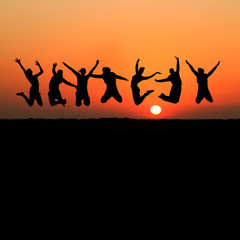 silhouette of friends jumping on beach during sunset