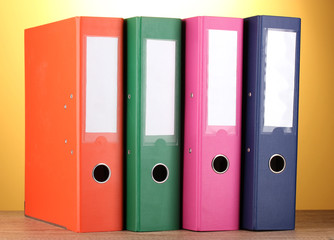 bright office folders on wooden table on yellow background.