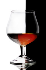 Glass of cognac on white-black background