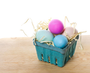 Small green basket of colored eggs and straw