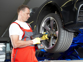 Motor mechanic in a garage is changing a tyre