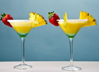 2 Cocktails mit Früchten vor blauem Hintergrund