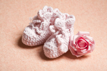 Pink baby shoes on peach background