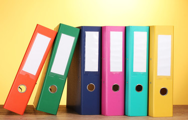 bright office folders on wooden table on yellow background