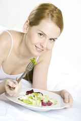 Obraz na płótnie Canvas portrait of lying down woman eating salad